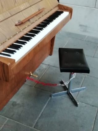 De kruk is nu met een rood-witte ketting aan de piano verbonden.