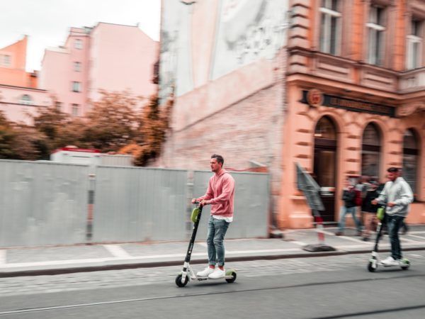 Twee mannen rijden beiden op een elektrische step in Praag.